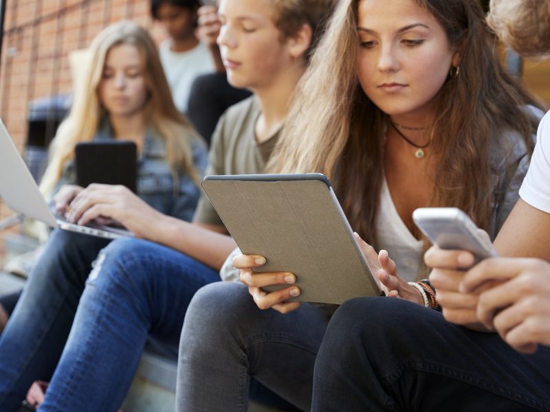 Teenage Students Using Digital Devices On College Campus