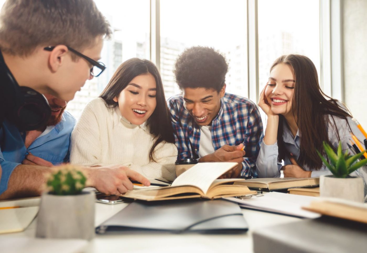 4 students reviewing textbooks scattered across a table